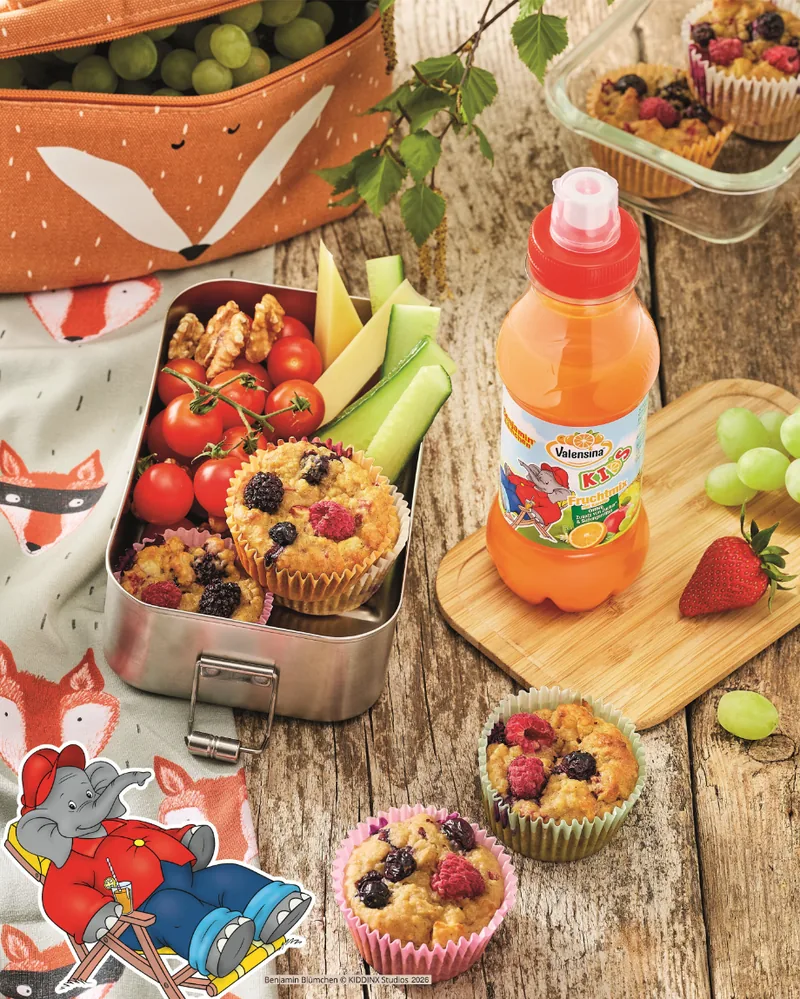 Brotdose mit Muffins und Obst neben einer Flasche Valensina KIDS