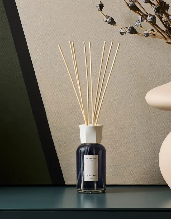 Stäbchendiffuser Millefiori Milano Notturno mit blauer Flüssigkeit auf einem Sideboard