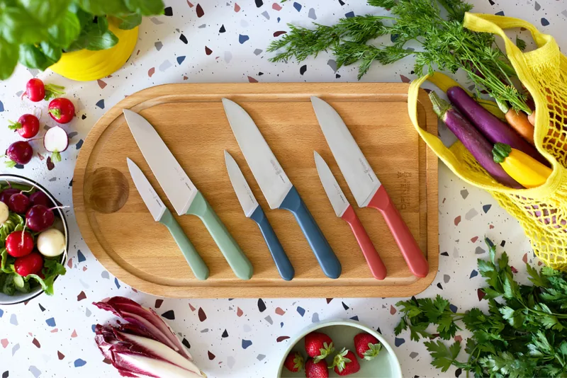 Opinel Juste Messer in drei Farben auf einem Holzbrett mit Gemüse