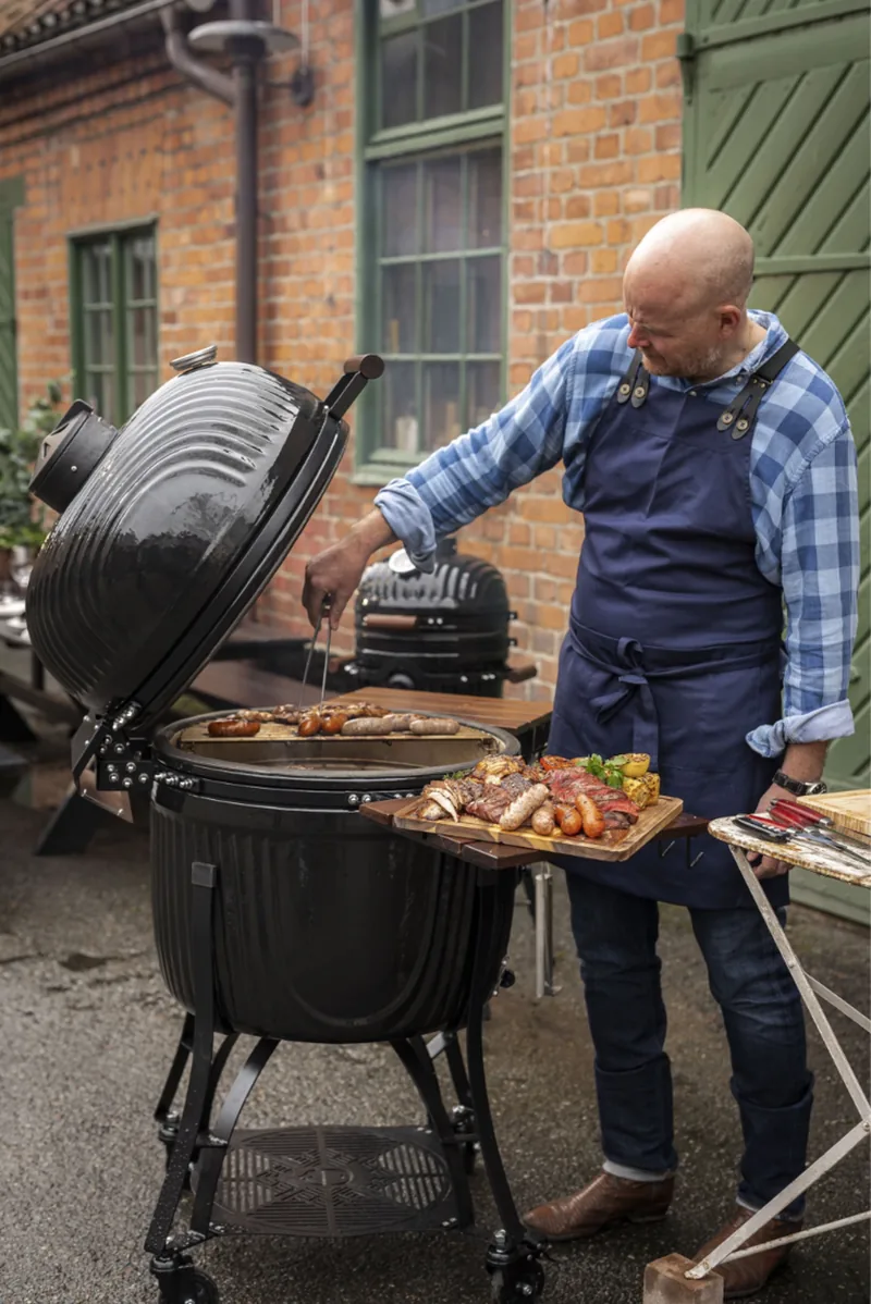 Mann grillt am Kamado Sumo Icon Maxi im Garten
