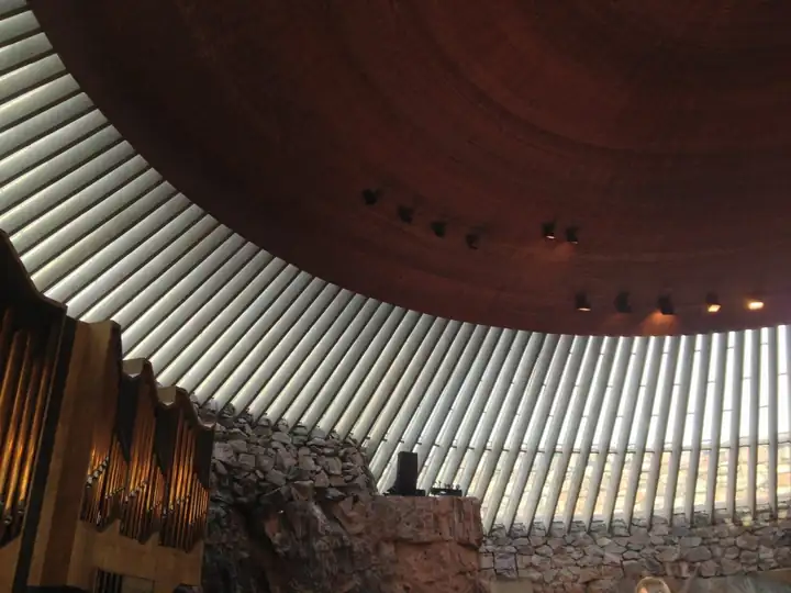 Innenraum der Felsenkirche Temppeliaukio mit Kupferkuppel, Lichtband aus Glas und Wänden aus Fels