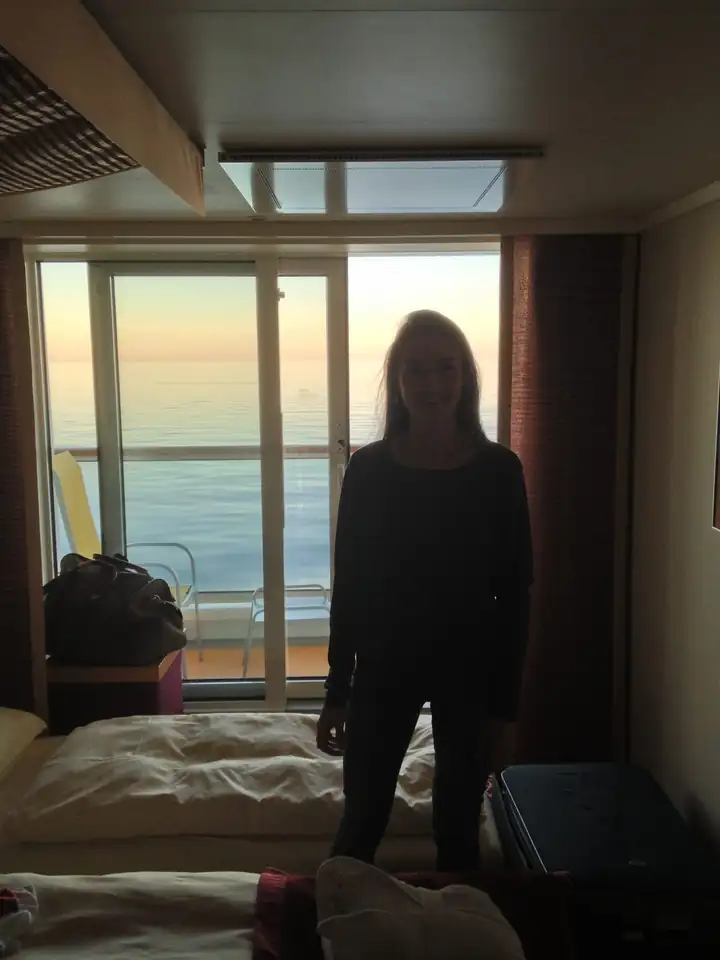 Balkonkabine auf der AIDAmar mit Betten und Glastür zum Balkon, dahinter die Ostsee im Morgenlicht