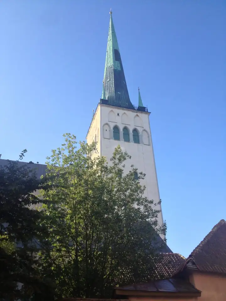 Weißer Turm der Olaikirche in Tallinn mit grüner Spitze vor blauem Himmel