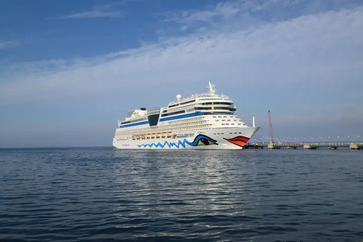 AIDAmar liegt vor Tallinn im ruhigen Wasser der Ostsee unter blauem Himmel