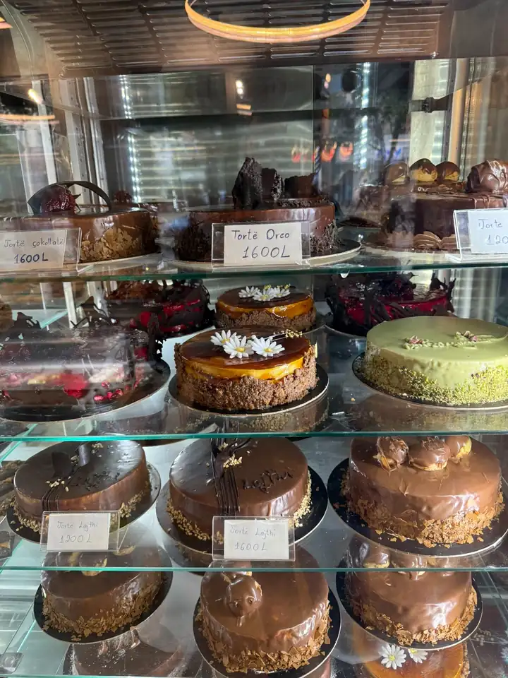 Vitrine mit Schokoladentorten, Pistazientorte und Karameltorte, Preisschilder mit 1200 und 1600 Lek