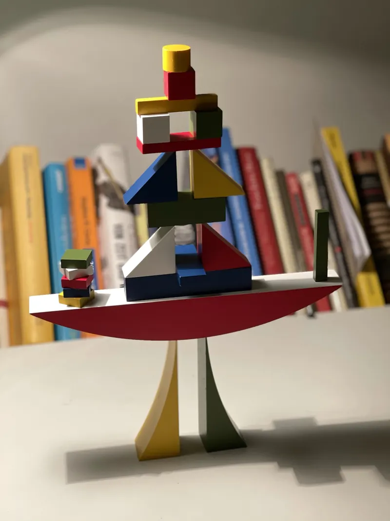 Bauhaus Bauspiel als hoher Aufbau mit Segeln aus blauen und gelben Dreiecken auf einem roten Bogen, getragen von zwei geschwungenen Stützen