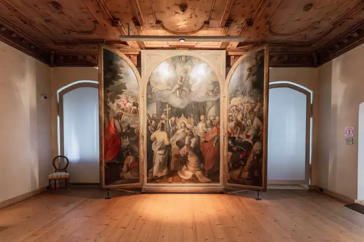 Saal in der Hofburg Brixen mit großem Flügelaltar, Holzdecke und hellem Holzboden