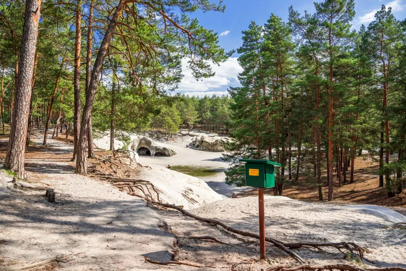 Grüner Stempelkasten der Harzer Wandernadel vor den Sandhöhlen im Heers