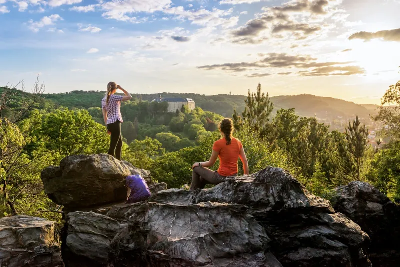 Wanderinnen auf Felsen der Teufelsmauer mit Blick auf Schloss Blankenburg