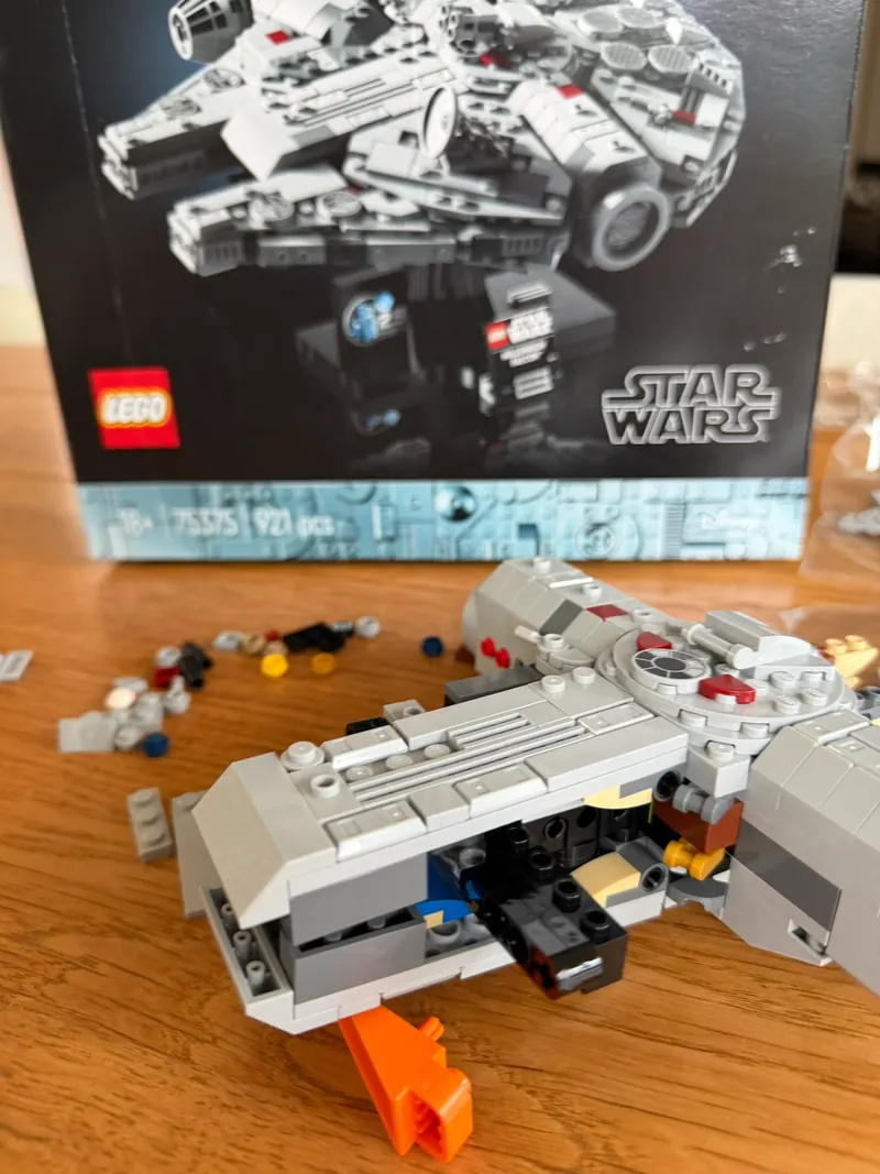 Teilweise gebauter Rumpf des LEGO Millennium Falcon mit grauer Hülle und Radarschüssel vor dem Karton mit der Aufschrift 75375 und 921 Teile