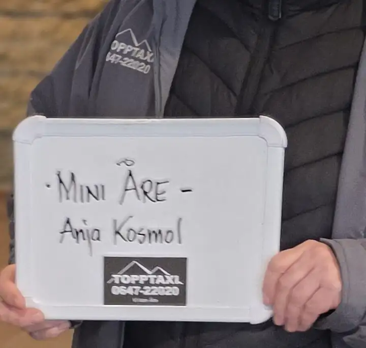 Weiße Tafel mit der Aufschrift Mini Åre und Anja Kosmol, gehalten bei der Abholung am Flughafen