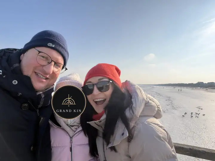 Herausgeber Lars Laschinski mit Familie in Wintermützen an der Ostsee in Ahlbeck, dahinter Strand und Eis, das Gesicht des Kindes ist mit dem GRAND KIN Logo verdeckt