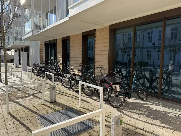 Fahrräder an Bügeln vor der Fassade des the breeze mit Glasfronten und Holzlamellen