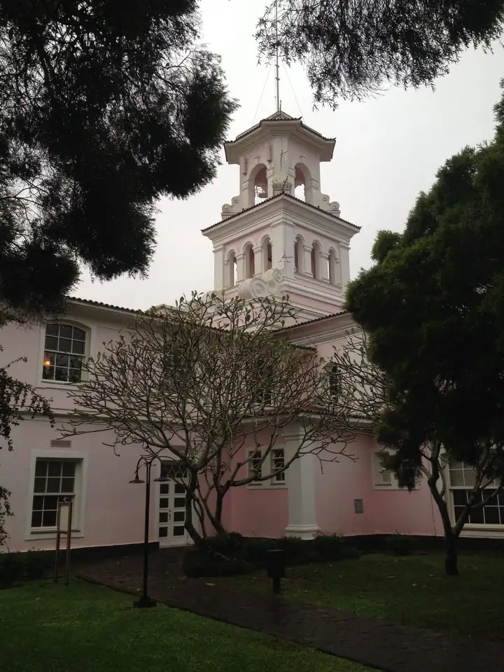 Turm des Hotel das Cataratas mit weißem Glockenaufsatz über der rosa Fassade, eingerahmt von Bäumen