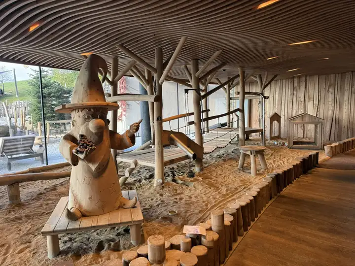 Indoor Sandwald mit geschnitzter Zaubererfigur und Holzkonstruktionen