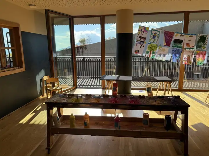 Malatelier mit Farbtöpfen, Staffeleien und Kinderbildern an einer Leine