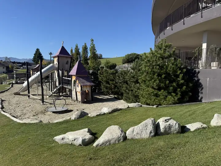 Spielplatz mit Holztürmen und Röhrenrutsche vor dem Hotel Familiamus