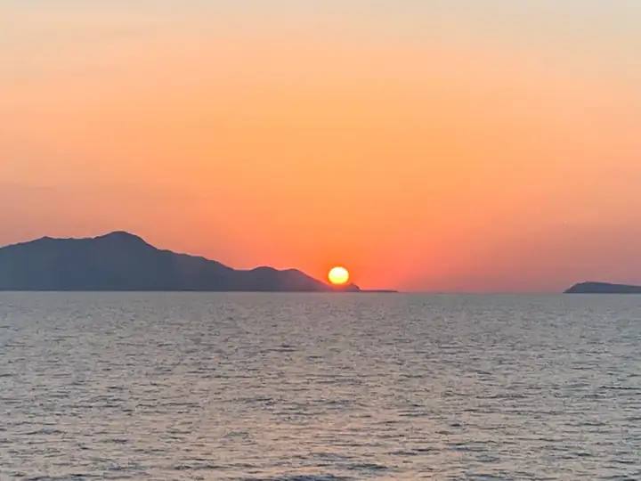 Sonnenuntergang über dem Meer, die Sonne sinkt hinter einer Insel