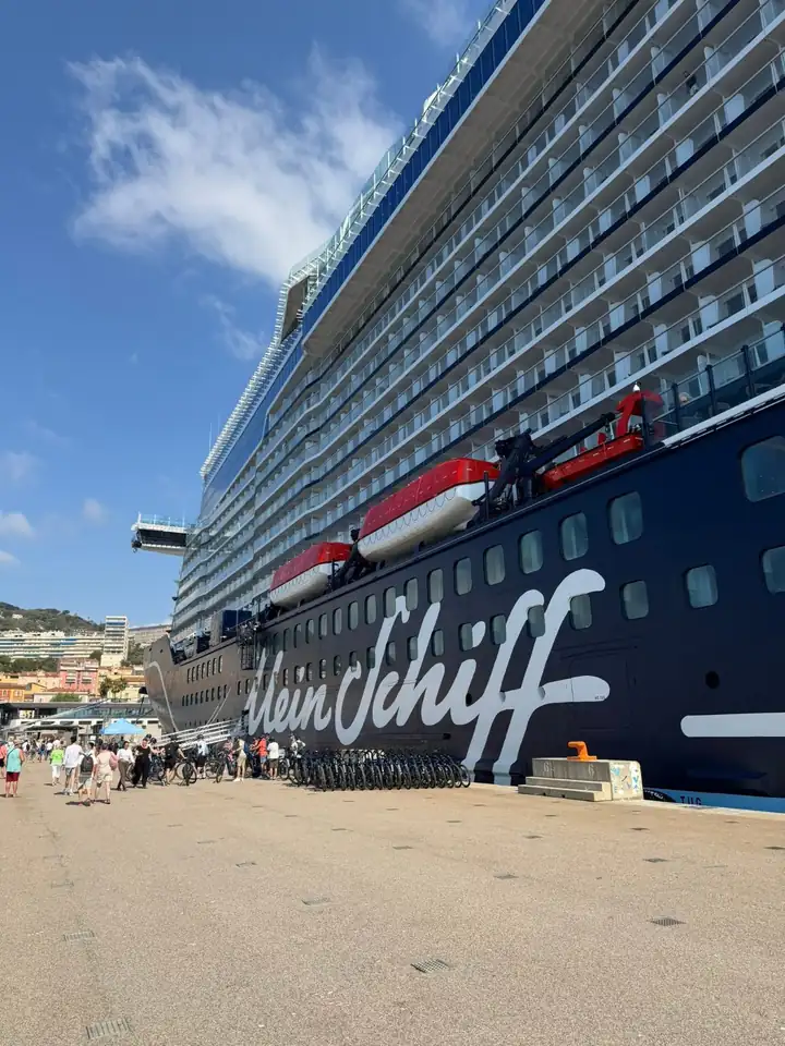 Die Mein Schiff Flow am Pier, am Rumpf der Schriftzug Mein Schiff, davor Fahrräder und Gäste auf dem Kai