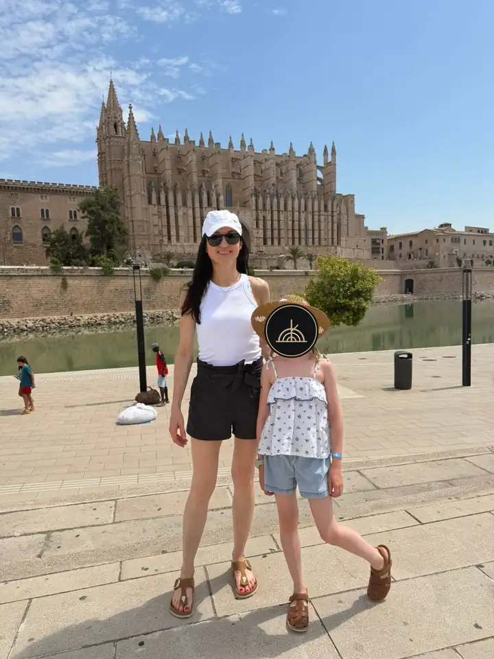Mutter und Tochter vor der Kathedrale La Seu in Palma, das Gesicht des Kindes ist verdeckt