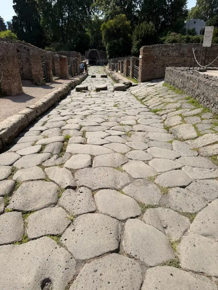 Römische Straße in Pompeji aus großen, glatten Pflastersteinen zwischen alten Mauern