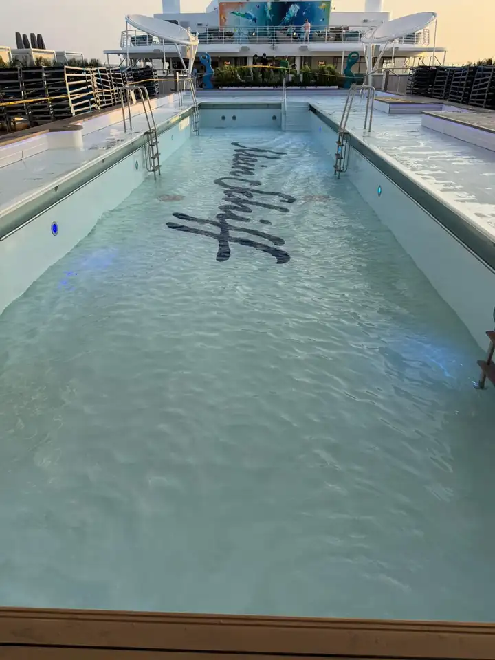 Langes Schwimmbecken an Deck mit dem Schriftzug Mein Schiff am Grund, ringsum Liegen