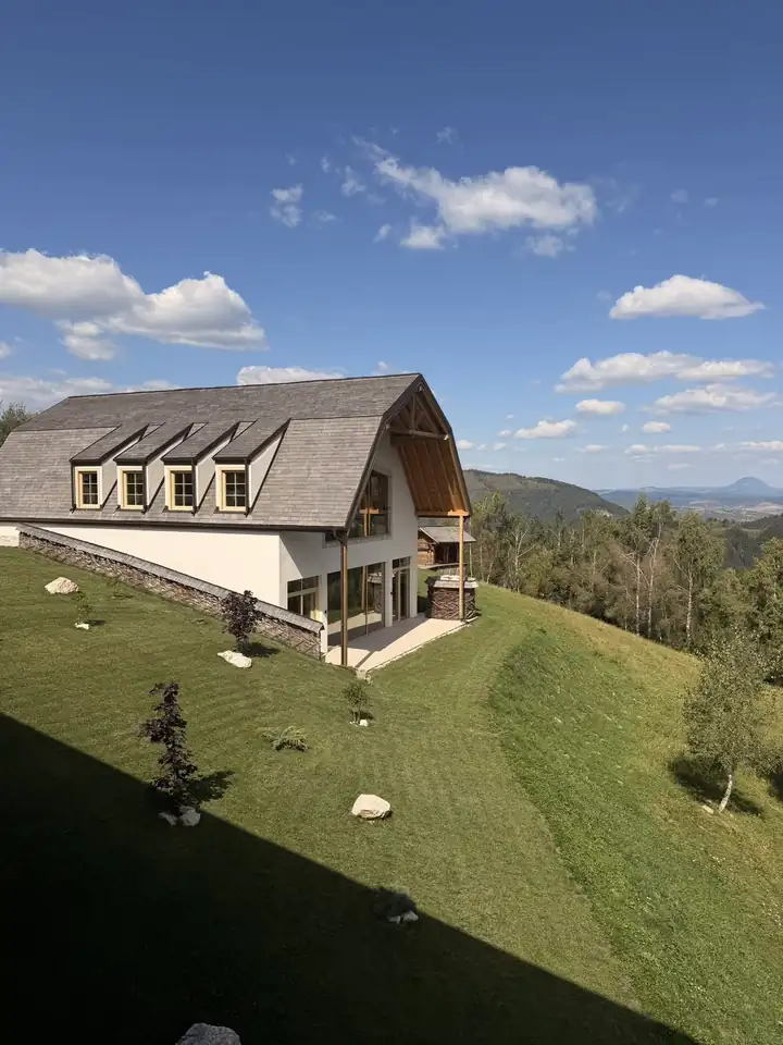 Villa mit Schindeldach, Gauben und Glasfront am Hang von MATCA