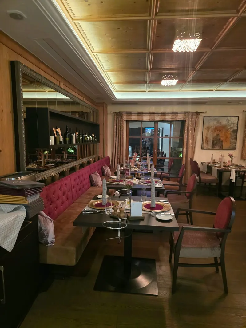 Restaurant mit Kassettendecke aus Holz, weinroter Polsterbank, gedeckten Tischen und Spiegeln