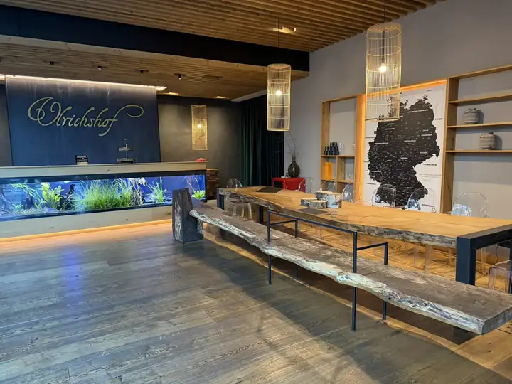 Empfang mit Aquarium im Tresen und Schriftzug Ulrichshof, daneben eine lange Tafel aus Altholz vor einer Deutschlandkarte